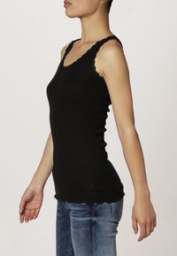 Zwarte mouwloze ribben tanktop met een scalloped halslijn en zoom, aansluitende silhouet, met een gestructureerde stof en slanke schouderbanden.