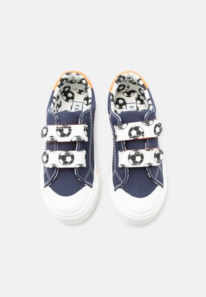 Tmavomodré detské tenisky s bielymi špičkami, dvoma suchými zipsami s motívom futbalovej lopty a vnútornou podšívkou s potlačou futbalových lôpt.