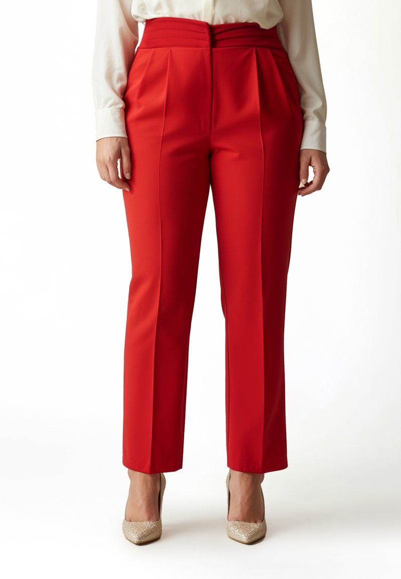 Rote, hoch taillierte Hose mit Falten, maßgeschneidertem Schnitt und glattem Stofffinish, kombiniert mit beigen, funkelnden High Heels.