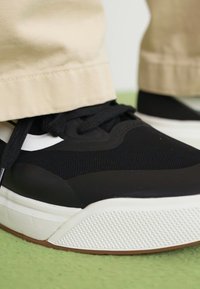 Sorte joggesko med et pustende mesh-overdel, hvit såle og teksturert gummiyttersåle. Har sorte snøringer og subtile design detaljer.
