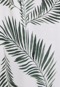 Zielony wzór liści palmowych na białym tle, z różnymi odcieniami zieleni oraz drobnymi szczegółami w teksturze i kształcie liści.