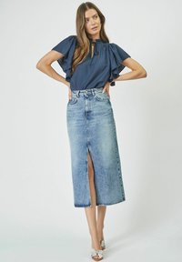 Navy blouse with ruffle sleeves and keyhole neckline, paired with a light-wash denim skirt featuring a front slit and high waist.