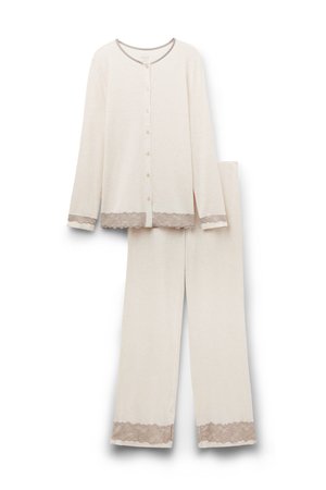 Ensemble de pyjama beige à manches longues avec des bordures en dentelle au bas et aux poignets. Le haut présente un col rond et des fermetures à boutons ; le pantalon a une coupe décontractée.