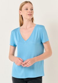 Jasnoniebieski t-shirt z krótkim rękawem i dekoltem w serek, wykonany z gładkiego materiału. Posiada luźny krój i prosty design bez ozdobników.