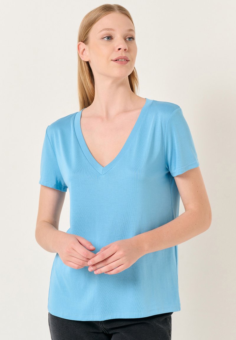 Jasnoniebieski t-shirt z krótkim rękawem i dekoltem w serek, wykonany z gładkiego materiału. Posiada luźny krój i prosty design bez ozdobników.