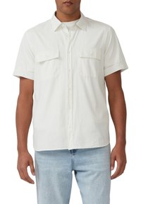 Korte mouwen overhemd met knopen in het wit, gemaakt van gestructureerde stof. Bevat twee borstzakken en een standaardkraag. Gecombineerd met lichtblauwe jeans.