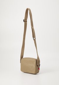 Borsa a tracolla beige di forma rettangolare, realizzata in tessuto liscio, con chiusura a zip e un accento rosa sul tirazip.