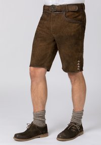 Bruine suède shorts met een getailleerde pasvorm, voorzien van een tailleband, decoratieve knopen aan de zoom, en gecombineerd met grijze wollen sokken en donkere schoenen.