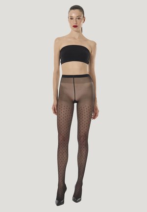 Svarta strumpbyxor med prickar och genomskinlig textur, hög midja och figurnära design, kombinerade med ett svart axelbandslöst linne och högklackade skor.