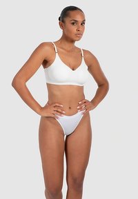 White wireless bra with adjustable straps paired with white thong. Smooth texture, minimalist design, classic cut.
