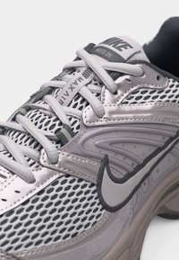 Κοντινό πλάνο γκρι αθλητικού παπουτσιού Nike Air Max Moto 2K με άνω μέρος από δίχτυ, λεπτομερές ράψιμο και ορατά κορδόνια.