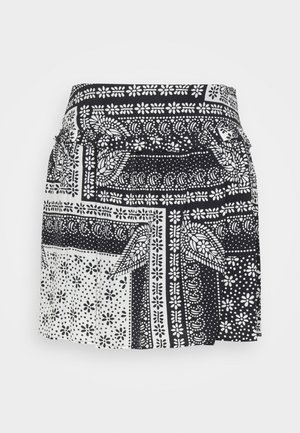 Gonna bianca e nera con intricati motivi floreali e geometrici, pieghe e una vita elasticizzata per un facile indossamento.
