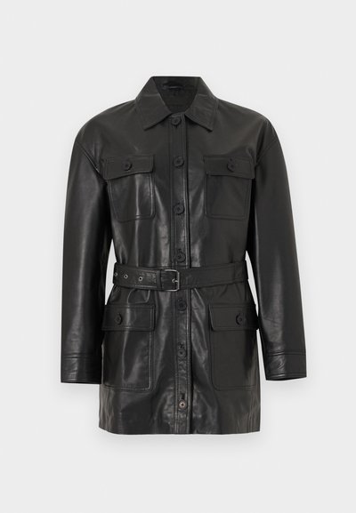 Must nahast pikkade varrukatega jakk nööpidega sulgemisega, neli nööpidega kaetud taskut ja vöökohal sobiv rihm.