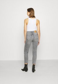 Vaqueros gris de cintura alta con un diseño de pierna recta, que presentan un parche de cuero en la parte trasera de la cintura y dos bolsillos traseros.