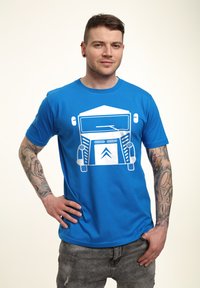 Modrá bavlněná tričko s bílým grafickým motivem vintage vozidla na přední straně. Krátké rukávy, kulatý výstřih a volný střih.