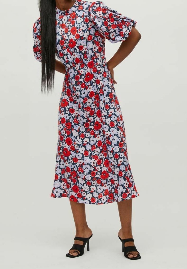 Robe midi fleurie avec un corsage ajusté, des manches bouffantes, des fleurs multicolores rouges et blanches sur un fond bleu marine, tissu lisse, ourlet à couches.