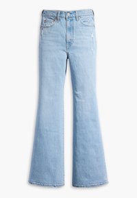 Jean en denim bleu clair taille haute avec jambes évasées, poches avant, fermeture par boutons, et légère usure sur la cuisse droite.