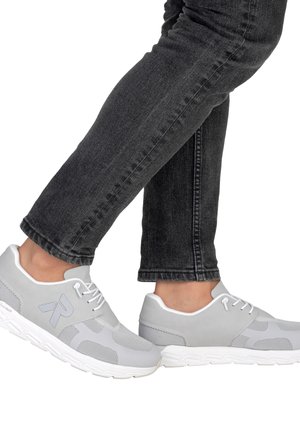 Light gray sneakers with mesh details and white accents; features a rounded toe, laces, and a textured sole. Worn with dark jeans.