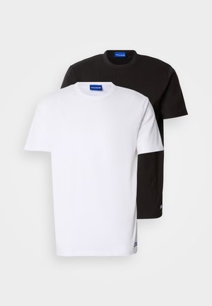 Kaksi T-paitaa pinottuna: yksi valkoinen ja yksi musta. Lyhyet hihat, pyöreät kaula-aukot, puuvillakangasta. Kaula-aukossa pieni sininen logo.