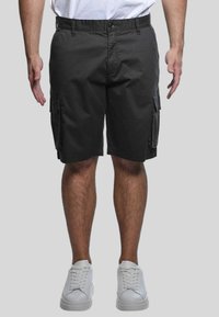 Pantaloni cargo in tessuto grigio scuro con vestibilità comoda, dotati di tasche laterali e chiusura con bottone in vita. Abbinati a sneakers bianche.