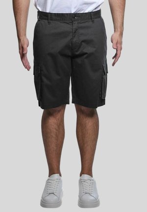 Pantaloni cargo in tessuto grigio scuro con vestibilità comoda, dotati di tasche laterali e chiusura con bottone in vita. Abbinati a sneakers bianche.