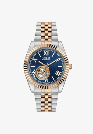 Automatische Uhr aus Silber und Roségold mit einem blauen Zifferblatt, römischen Ziffern und einem sichtbaren Uhrwerk bei 6 Uhr. Stilvolles Gliederarmband.