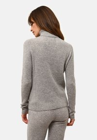 Grå, ribbad stickad polotröja med långa ärmar, med en figurnära design och en mjuk textur, ihopparad med matchande grå byxor.