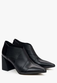 Czarne skórzane botki za kostkę ze szpiczastym noskiem, z wyraźnym słupkowym obcasem oraz unikalnym krzyżującym się wzorem na wierzchu.