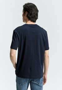 Camiseta de manga corta en color navy, hecha de una tela suave y lisa. Cuello redondo, corte relajado y sin diseños o patrones prominentes. Adecuada para uso casual.