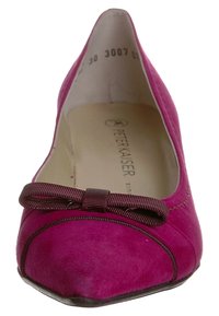Ballerina in suede fucsia con punta tonda, un piccolo fiocco di raso scuro come dettaglio e cuciture sottili lungo il bordo.