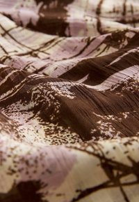 Bruine en roze gestreepte stof met een gestructureerd oppervlak, voorzien van abstracte ontwerpen en strepen, die een gelaagde, vloeiende uitstraling creëren.