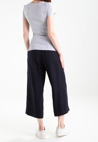 T-shirt grigio a maniche corte aderente abbinato a culotte largo di colore blu navy, indossato con sneakers bianche slip-on.