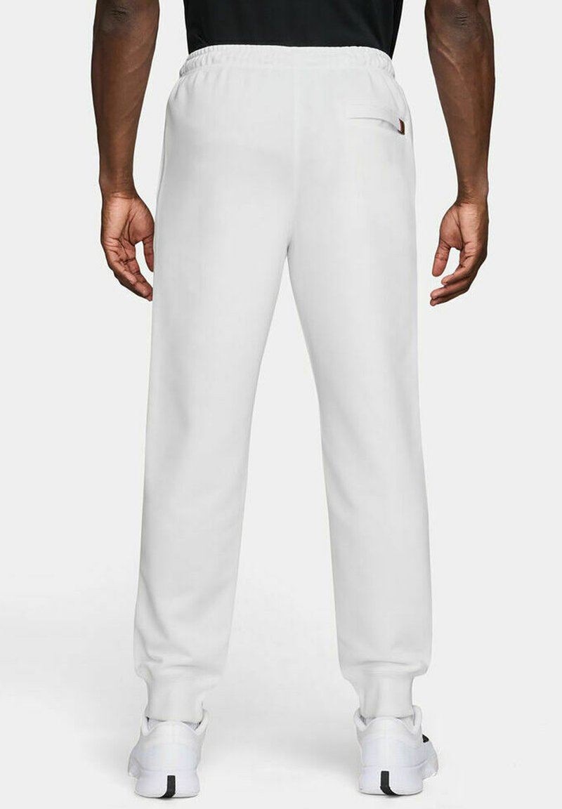 Weiße Jogginghose mit elastischem Bund, enganliegenden Knöcheln und einer einzelnen Gesäßtasche. Glatte Textur und lässiges Design.