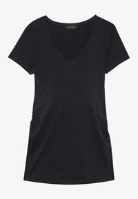 Melnā kreklā ar īsām piedurknēm un V-veida kakla izgriezumu, izgatavots no mīksta auduma, ar rušēšanas detaļām sānos, nodrošinot brīvu piegriezumu.