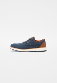 Zapatos de hombre con parte superior de tejido texturizado en azul marino, detalles en cuero marrón, punta redonda y suela de goma blanca. Diseño clásico de cordones.