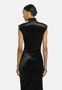 Schwarzes, ärmelloses Samtkleid mit hohem Kragen und gerafftem Detail an der Taille, das eine lange, figurbetonte Silhouette hat.