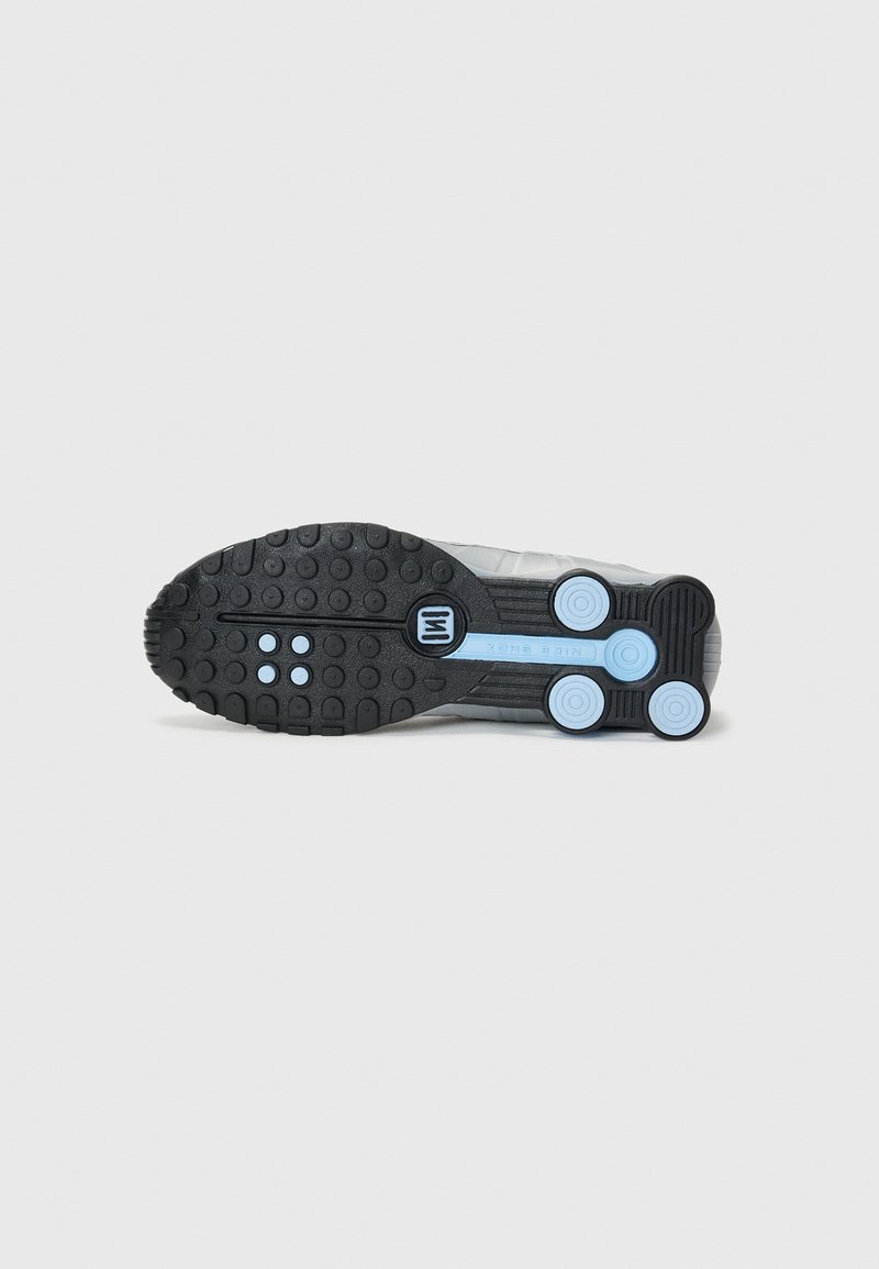 Suela de zapato con una base de goma negra, patrón de agarre texturizado y acentos circulares en azul claro. Diseñada para ofrecer tracción y durabilidad.