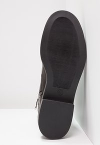 Czarna podeszwa buta z teksturowanym gumowym dnem. Zamek błyskawiczny po boku, gładka skórzana cholewka oraz mały obcas dla lepszej przyczepności.