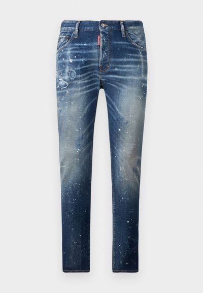 Tummansiniset farkut, joissa on haalistuneita alueita, kulutuspisteitä ja valkoisia maalisäyhkkiä. Suora lahkeiden muotoilu klassisella viiden taskun asettelulla.