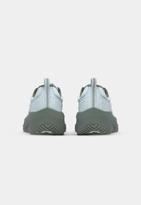 Chaussures de sport bleu clair avec une semelle grise épaisse, présentant des détails texturés sur le dessus et une sangle de traction à l'arrière.