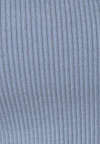 Tessuto a coste blu chiaro con una texture sottile, caratterizzato da linee verticali. Il tessuto appare elastico e morbido. Nessun ulteriore dettaglio visibile.