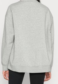 Grå sweatshirt, avslappnad passform, mjuk textur, ribbad fåll och ärmslut, bred rund halsringning och sömlös baksidedesign. Lämplig för vardagsbruk.