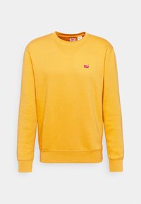 Gele sweatshirt van zachte katoen, met een ronde hals, lange mouwen en een klein rood Levi's-logo op de borst. Soepele textuur.