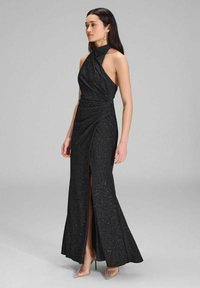 Schwarzes Abendkleid mit Neckholder, gewickeltem Design, hohem Schlitz und glitzernder Oberfläche. Bodenlang mit einer figurnahen Silhouette.