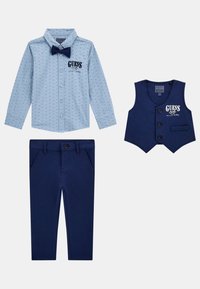Chemise bleu clair à boutons avec de petits motifs, gilet bleu marine avec trois boutons et pantalon bleu marine assorti. Tous les articles présentent un logo "GUESS".