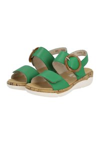 Sandales en cuir vert avec une semelle intermédiaire en liège, dotées de deux sangles réglables et d'un grand accent rond marron sur le côté extérieur.