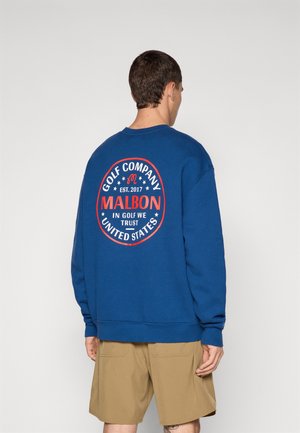 Blue sweatshirt with a circular red and white printed logo on the back, featuring text and stars. Made of soft fabric with a crew neck.