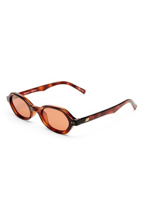 Gafas de sol ovaladas de carey con lentes de color ámbar y patillas finas, mostradas sobre fondo blanco.