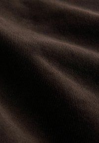 Brown textured fabric with a soft, velvety surface, featuring subtle ribbing and gentle folds, creating a rich visual depth.