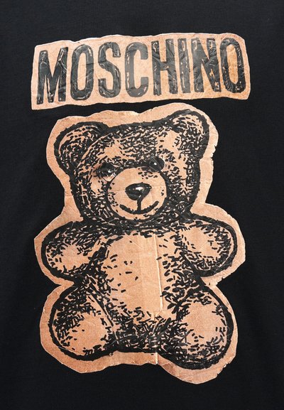 Γραφικό αρκουδάκι με υφή καφέ μοτίβου κάτω από το έντονο, φθαρμένο κείμενο «MOSCHINO» σε μαύρο φόντο.